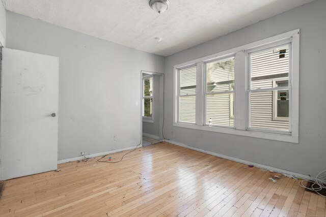 empty room with a textured ceiling and light wood-type flooring