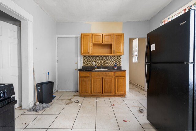 kitchen featuring black appliances, sink, light tile patterned floors, and backsplash