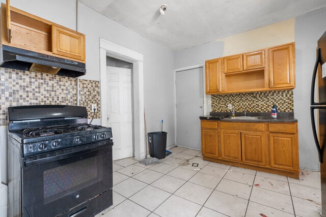 kitchen featuring backsplash, light tile patterned flooring, sink, and black gas range