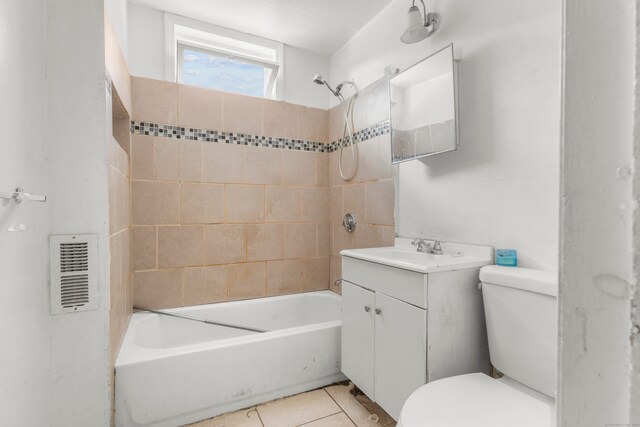 full bathroom with tile patterned floors, tiled shower / bath combo, vanity, and toilet