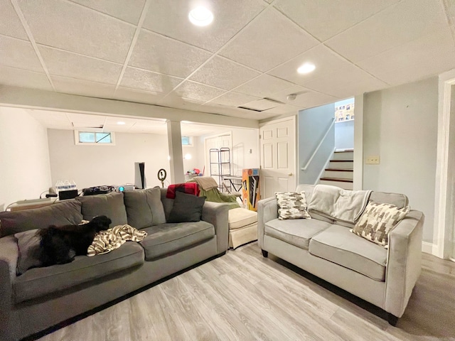 living room featuring a drop ceiling and light wood-type flooring