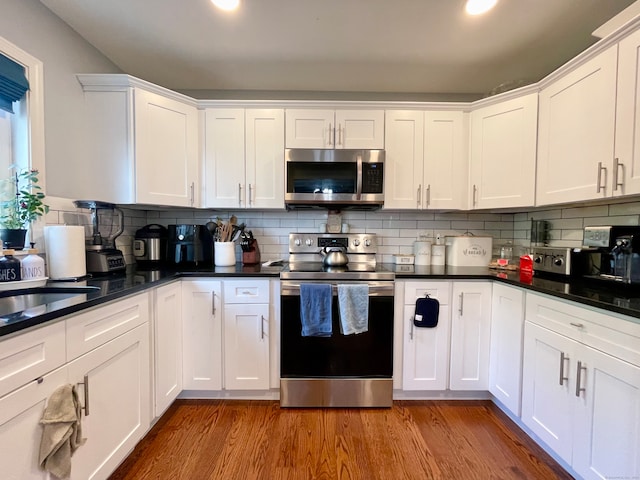 kitchen with hardwood / wood-style flooring, stainless steel appliances, and white cabinets