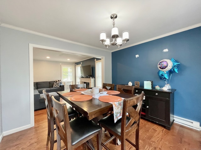 dining space featuring an inviting chandelier, crown molding, light hardwood / wood-style floors, and a baseboard heating unit