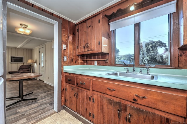 kitchen featuring wood walls, ornamental molding, sink, and light hardwood / wood-style flooring