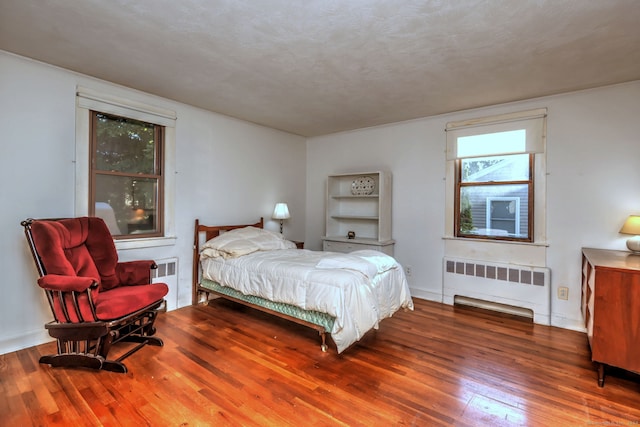 bedroom featuring radiator heating unit, a textured ceiling, and hardwood / wood-style flooring