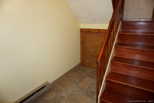 staircase featuring a textured ceiling, vaulted ceiling, and baseboard heating