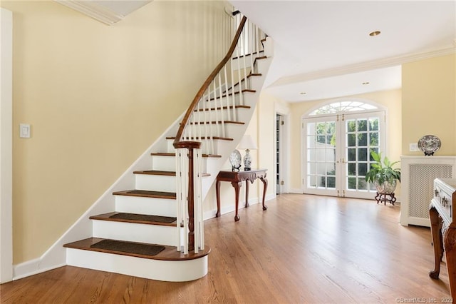 staircase with french doors, hardwood / wood-style floors, and crown molding