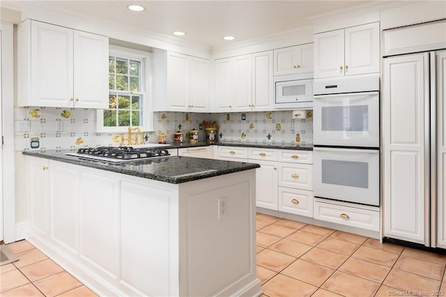 kitchen featuring white cabinets, light tile patterned floors, dark stone counters, and white appliances