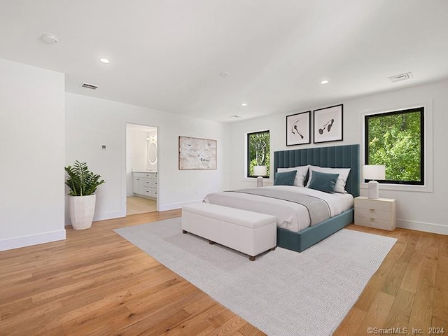 bedroom featuring connected bathroom and light hardwood / wood-style floors