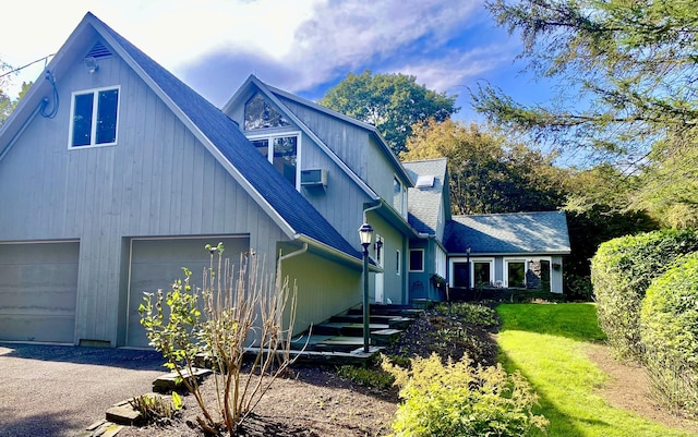 view of front of home featuring a garage, driveway, roof with shingles, and a front yard