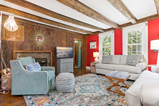 living room featuring beamed ceiling, hardwood / wood-style flooring, a fireplace, and wood walls