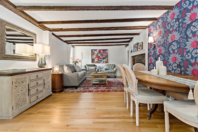 dining space with light wood-type flooring, a fireplace, and beam ceiling