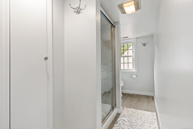 bathroom with wood-type flooring, walk in shower, and toilet