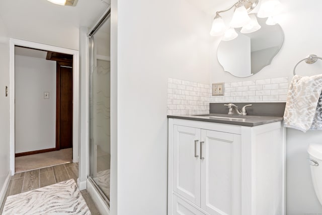 bathroom with toilet, hardwood / wood-style floors, an enclosed shower, decorative backsplash, and vanity