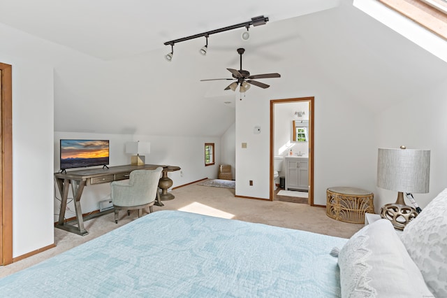 carpeted bedroom with ceiling fan, ensuite bath, and vaulted ceiling with skylight