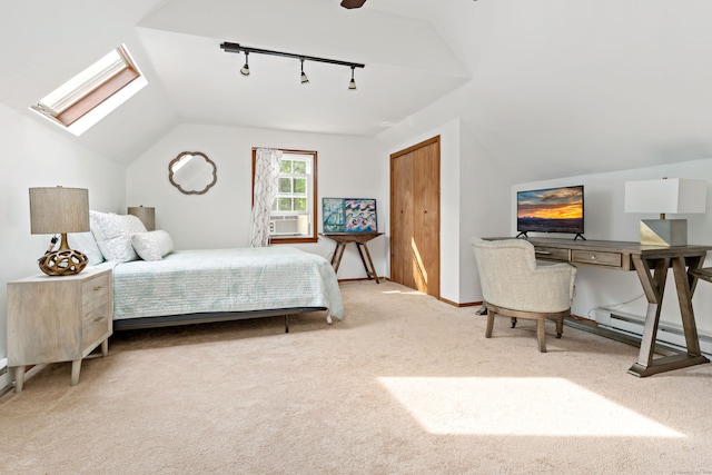 bedroom featuring ceiling fan, a closet, a baseboard heating unit, carpet floors, and vaulted ceiling with skylight