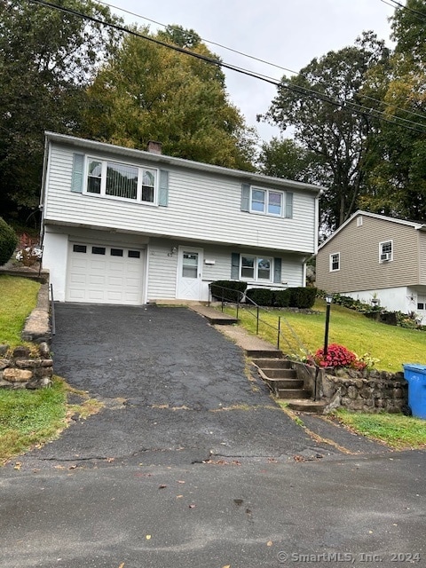 split foyer home featuring a front yard and a garage