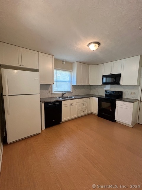 kitchen featuring light hardwood / wood-style floors, sink, decorative backsplash, black appliances, and white cabinetry