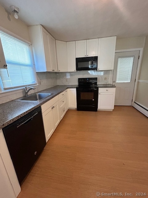 kitchen with sink, light hardwood / wood-style flooring, backsplash, white cabinetry, and black appliances