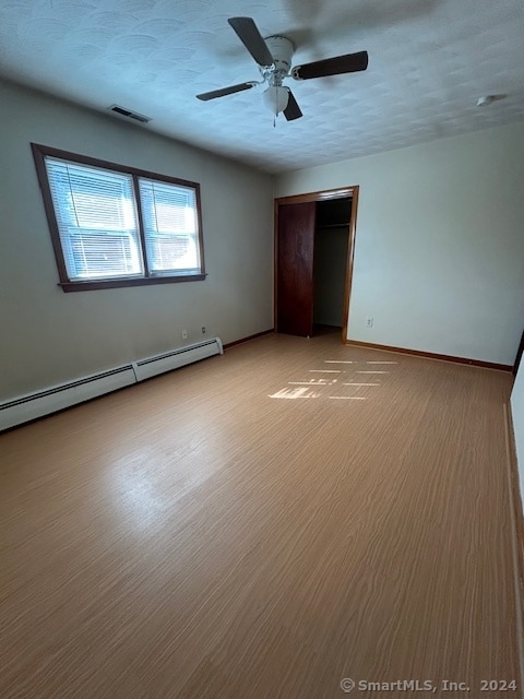 unfurnished bedroom with ceiling fan, a textured ceiling, light hardwood / wood-style floors, and a baseboard heating unit