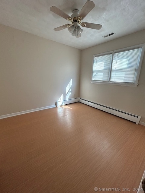 empty room featuring ceiling fan, a textured ceiling, baseboard heating, and light hardwood / wood-style floors