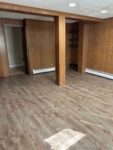 basement with wood walls, hardwood / wood-style flooring, and a baseboard radiator