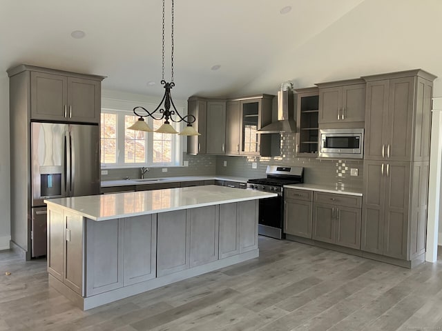 kitchen featuring a center island, appliances with stainless steel finishes, wall chimney range hood, and gray cabinetry