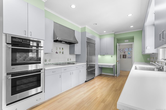 91 Open Gate Ln, Fairfield, CT 06890 - kitchen with stainless steel appliances, wall chimney range hood, a sink, crown molding, and recessed lighting