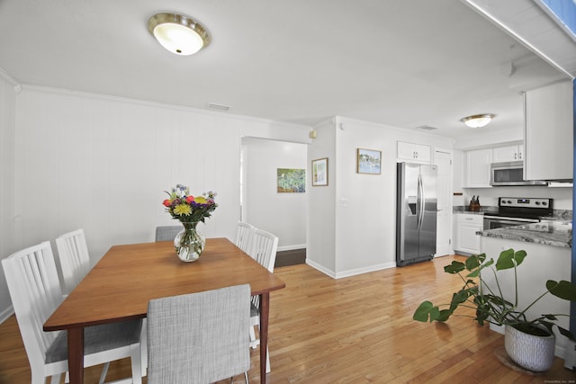 dining area featuring visible vents, baseboards, light wood-style floors, and ornamental molding