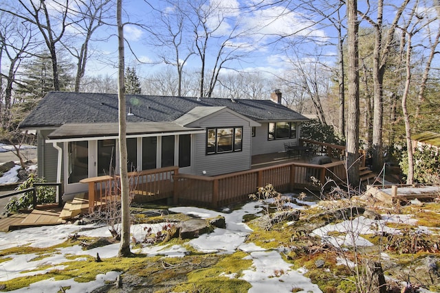 rear view of property with a chimney, a shingled roof, a deck, and a sunroom