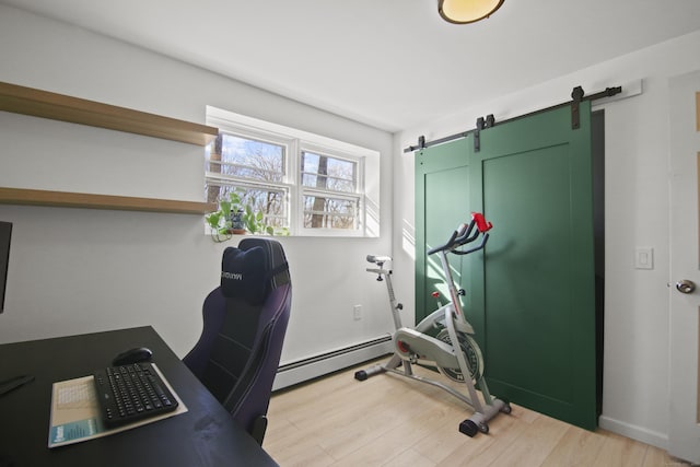 office space with a barn door, light wood-style floors, and a baseboard heating unit