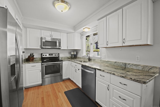 kitchen with ornamental molding, appliances with stainless steel finishes, light wood-style floors, white cabinets, and a sink