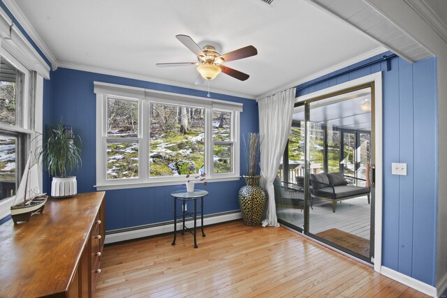 sitting room featuring a ceiling fan, baseboards, a baseboard radiator, light wood-style flooring, and crown molding