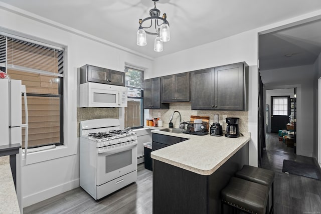 kitchen featuring hardwood / wood-style floors, tasteful backsplash, white appliances, sink, and pendant lighting