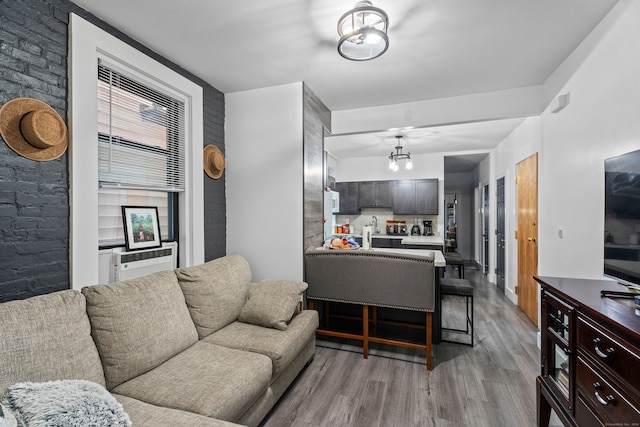 living room with cooling unit, light hardwood / wood-style flooring, and sink