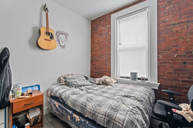 bedroom featuring wood-type flooring and brick wall