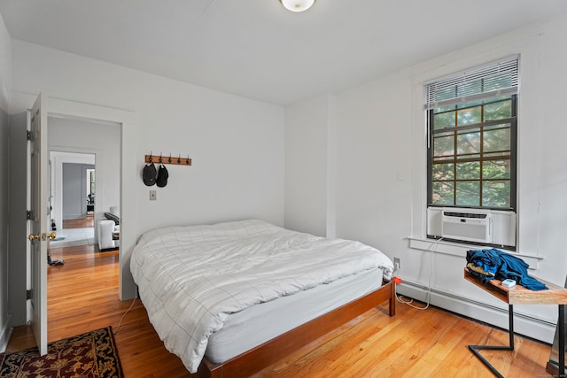 bedroom with wood-type flooring, cooling unit, and a baseboard radiator