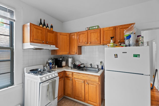 kitchen with light tile patterned flooring, white appliances, sink, and backsplash