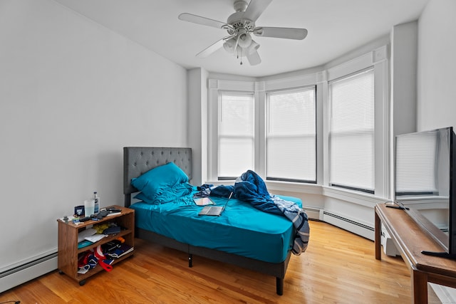 bedroom with ceiling fan, light wood-type flooring, and a baseboard heating unit