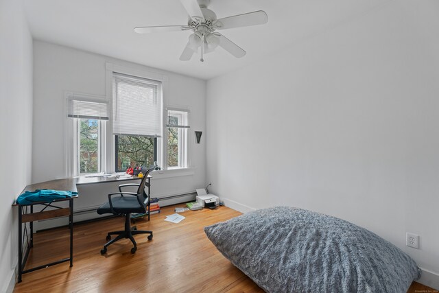 office featuring wood-type flooring, a baseboard heating unit, and ceiling fan