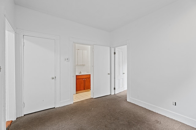 unfurnished bedroom with light colored carpet and connected bathroom