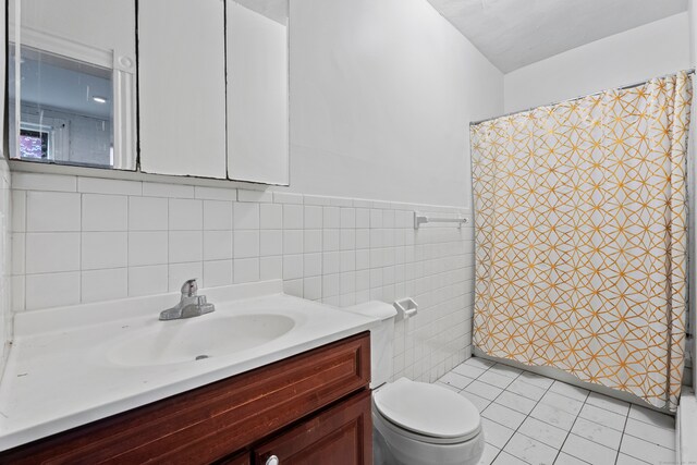 bathroom featuring vanity, tile walls, a shower with shower curtain, tile patterned floors, and toilet