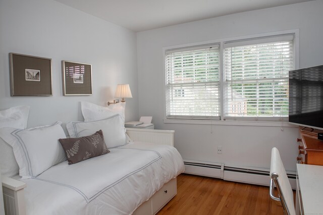 bedroom with a baseboard radiator and light hardwood / wood-style flooring