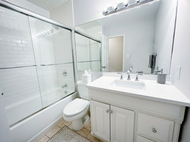 full bathroom with shower / bath combination with glass door, vanity, tile patterned flooring, and toilet