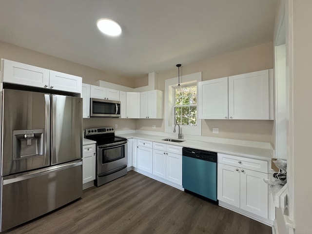 kitchen featuring appliances with stainless steel finishes, white cabinets, decorative light fixtures, dark hardwood / wood-style floors, and sink