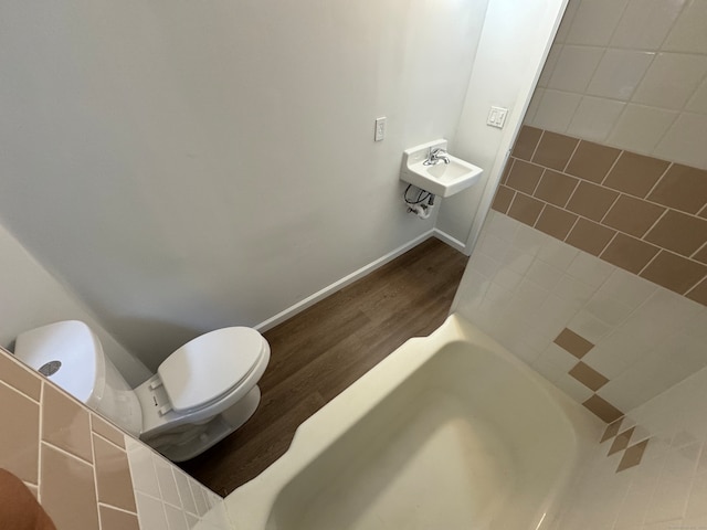 bathroom with a bathing tub, sink, hardwood / wood-style floors, and toilet