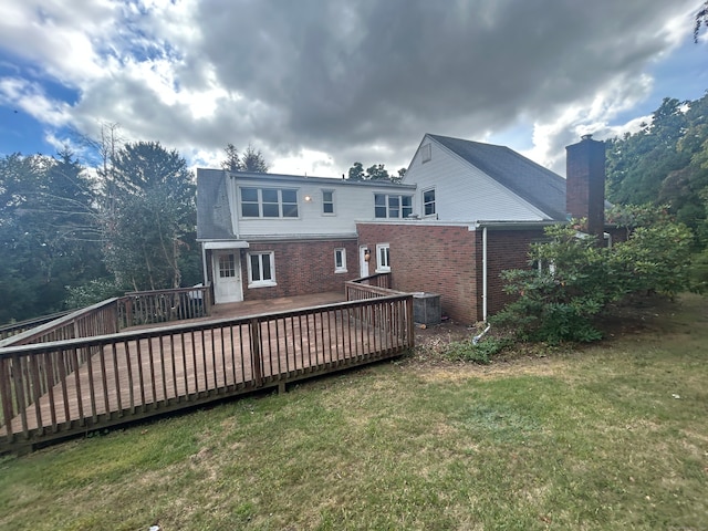 back of house featuring cooling unit, a wooden deck, and a lawn