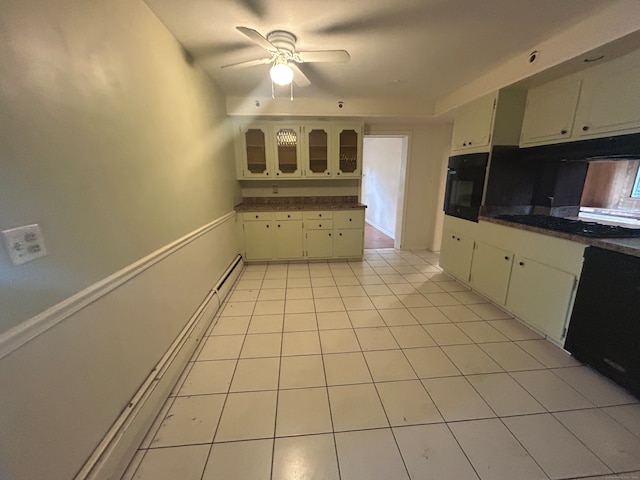 kitchen with light tile patterned flooring, stovetop, ceiling fan, oven, and cream cabinets