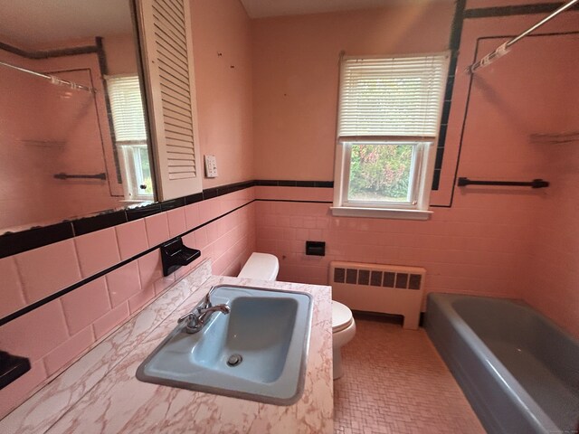 full bathroom with radiator, sink, toilet, and  shower combination