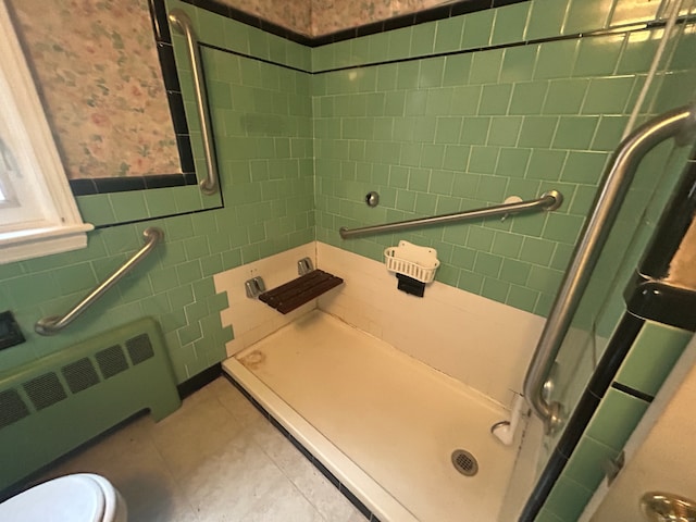 bathroom featuring tile walls, tile patterned flooring, radiator, a shower with shower door, and toilet